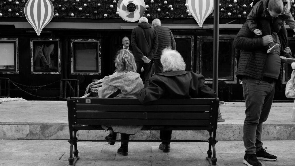 Black and white city street scene with people and holiday decorations.