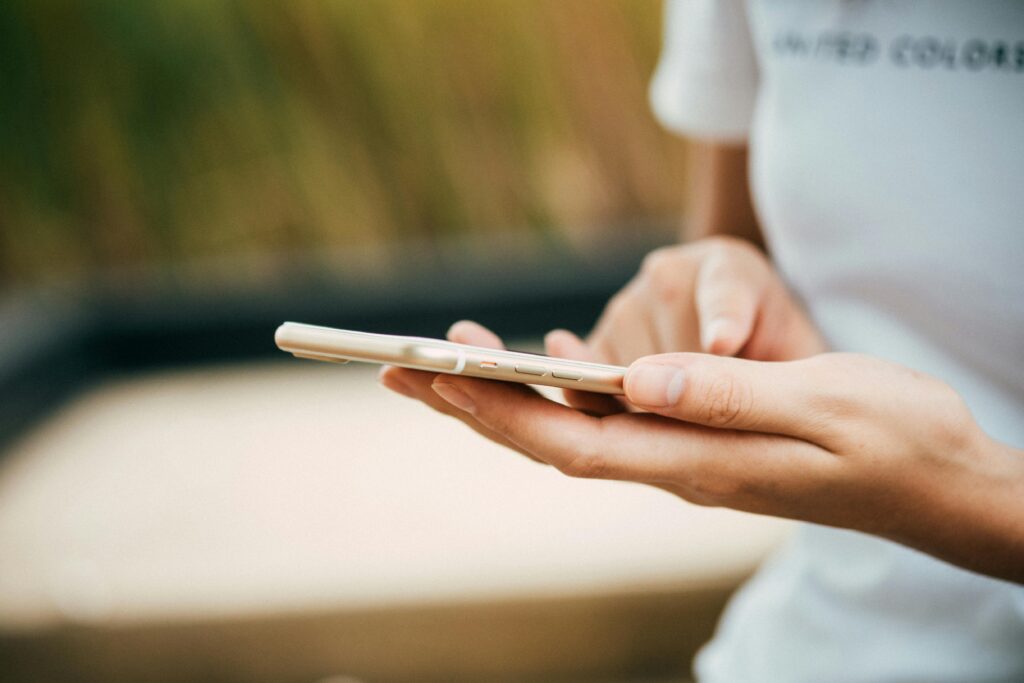 Close-up of a person using a smartphone outdoors, focusing on hands and device.