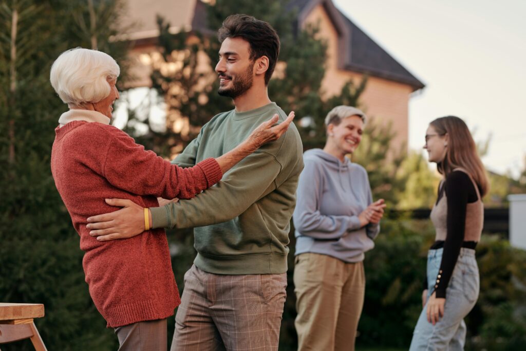 A joyful family gathering outdoors with diverse generations embracing and smiling.