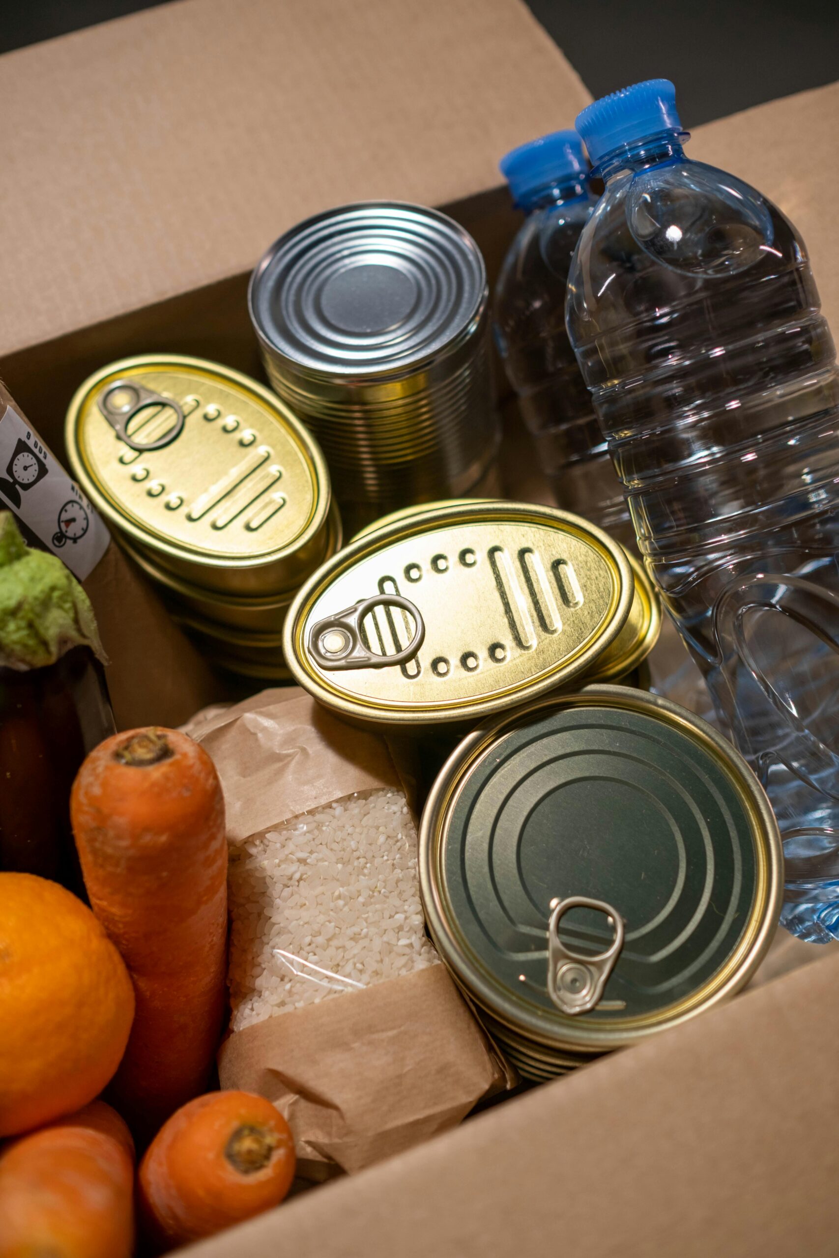 Box filled with essential food items including canned goods and fresh produce.